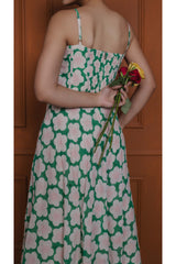Back view of green cotton silk midi dress with smocked back, adjustable straps, and flared hem